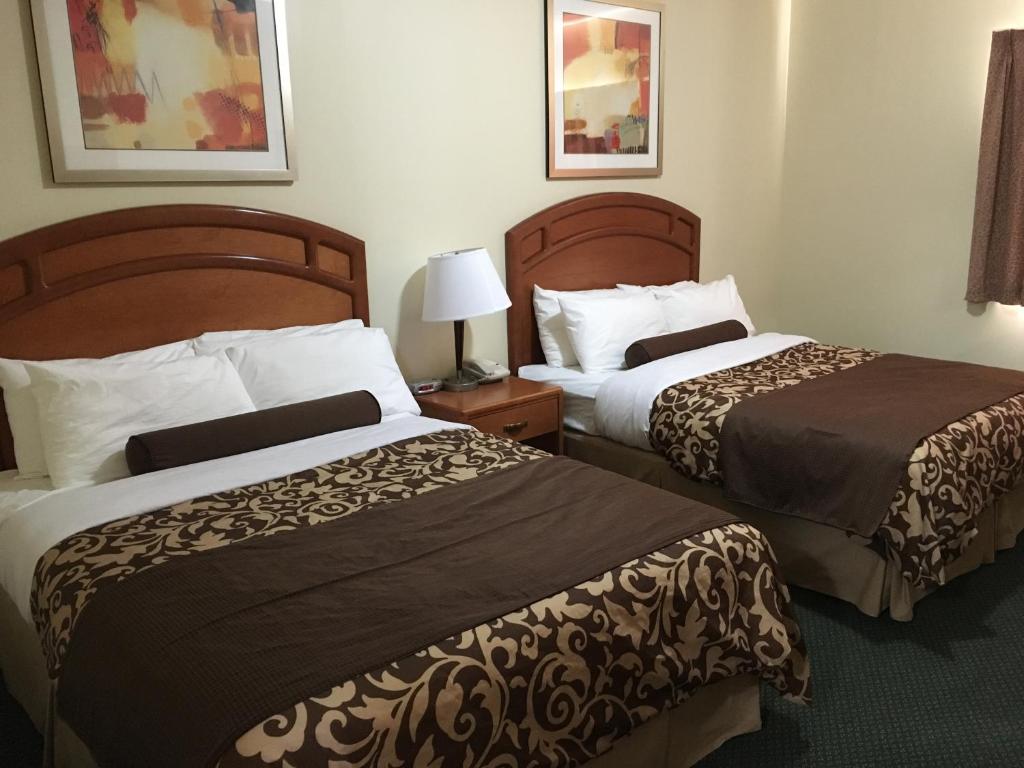 a hotel room with two beds and a lamp at Western Valley Inn in Valleyview