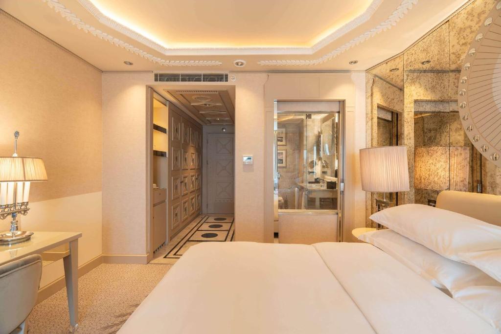 a bedroom with a white bed and a desk and a room at Wyndham Grand Istanbul Kalamış Marina Hotel in Istanbul