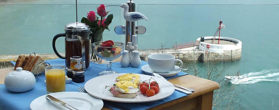 a breakfast table with a plate of food on a table with the water at The Watermark in Looe