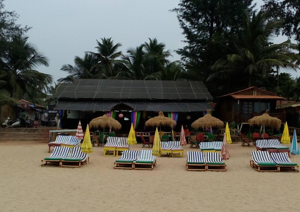 een groep strandstoelen en parasols op een strand bij Om Shanti Beach Stay Patnem in Patnem
