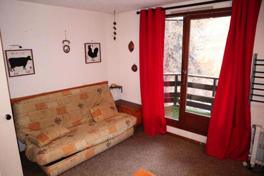 - un salon avec un canapé et une fenêtre avec des rideaux rouges dans l'établissement Résidence Le Pouzenc - Studio calme pieds de pistes MAE-3911, aux Orres