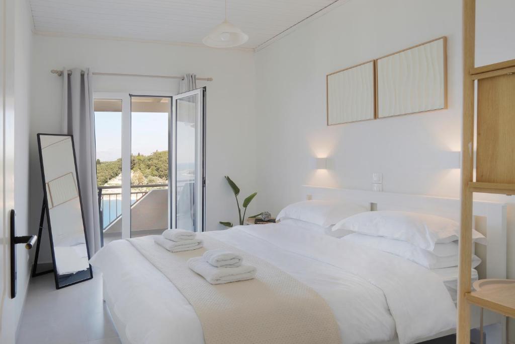 um quarto branco com uma cama grande e toalhas em Thea Studios em Kassiopi