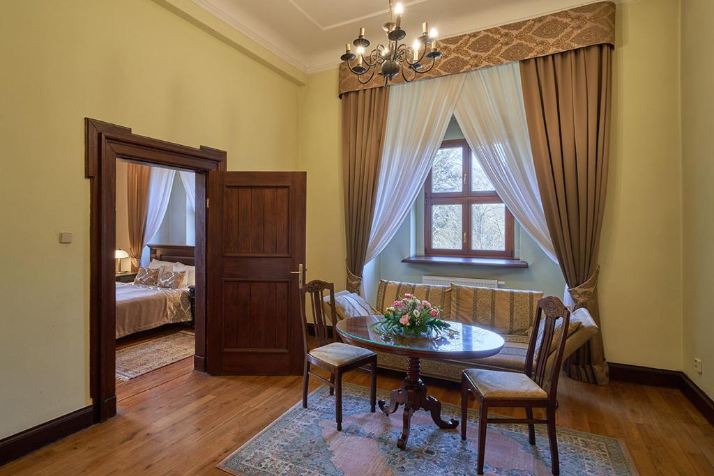 Elegant living room with chandelier, wooden furniture, and large window with draped curtains.