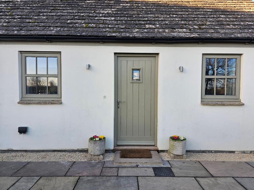 a white house with a green door and two windows at The Dairy in Swindon