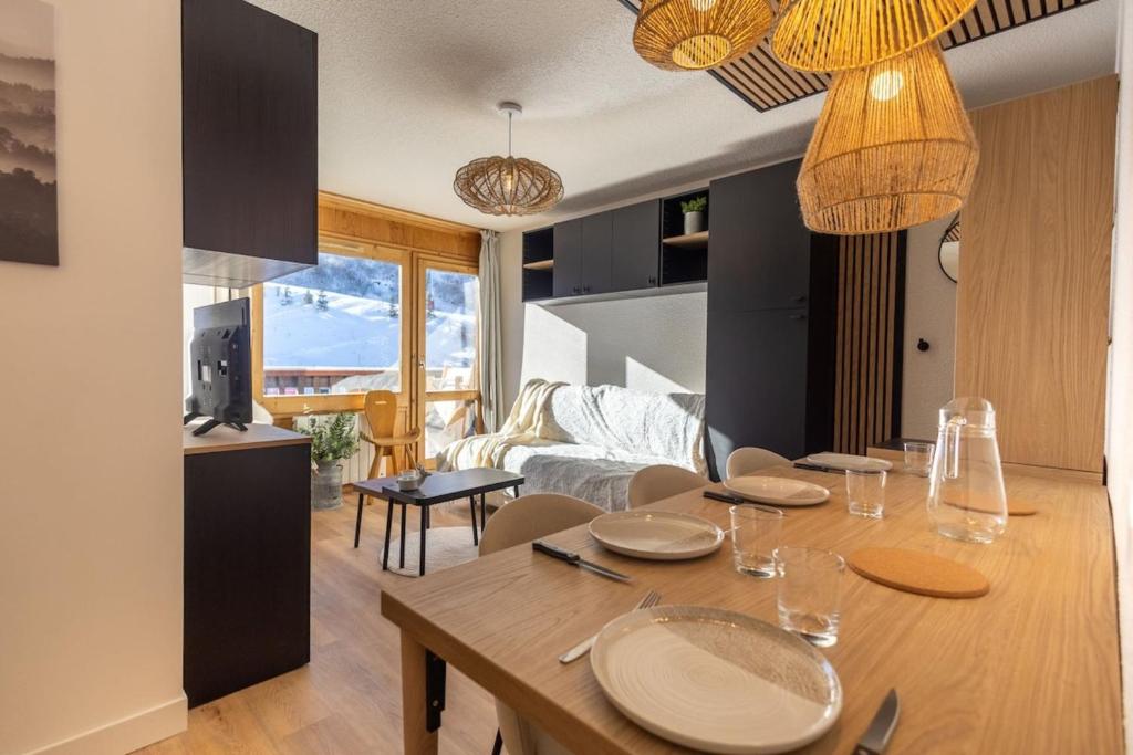 une salle à manger et un salon avec une table et des chaises dans l'établissement Cozy 4-Person Apartment at the Foot of the Slopes Méribel-Mottaret, à Les Allues
