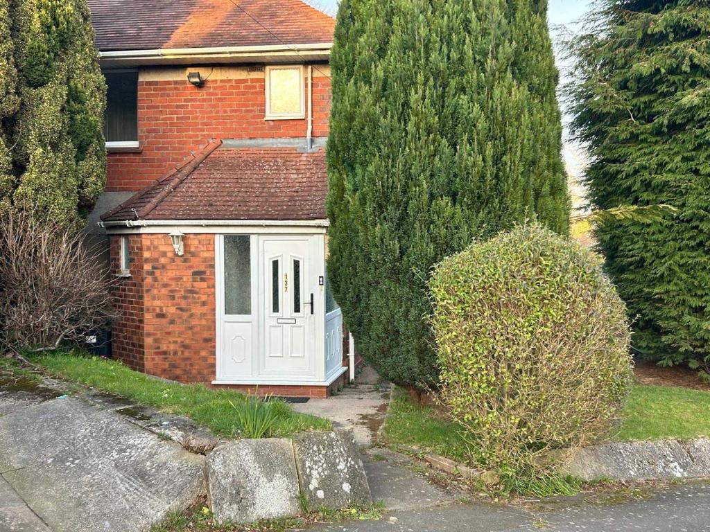 une maison avec une porte blanche et deux arbres dans l'établissement Cosy 3-Bed Retreat - Garden Parking & Bbq, à Birmingham