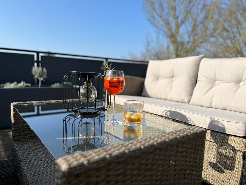 two glasses of wine on a glass table on a patio at Ferienwohnung am Pietzmoor in Schneverdingen