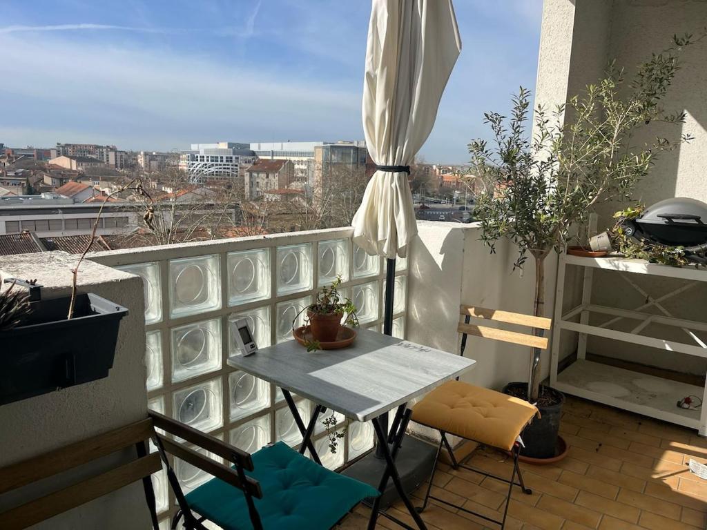 un balcon avec une table et une vue sur une ville dans l'établissement Le Sunny I T4, à Toulouse