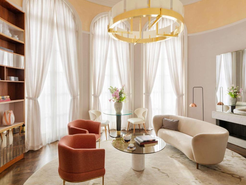 a living room with a table and chairs and a chandelier at Raffles Europejski Warsaw in Warsaw