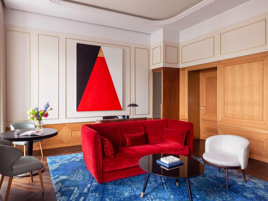 a living room with a red couch and a table at Raffles Europejski Warsaw in Warsaw