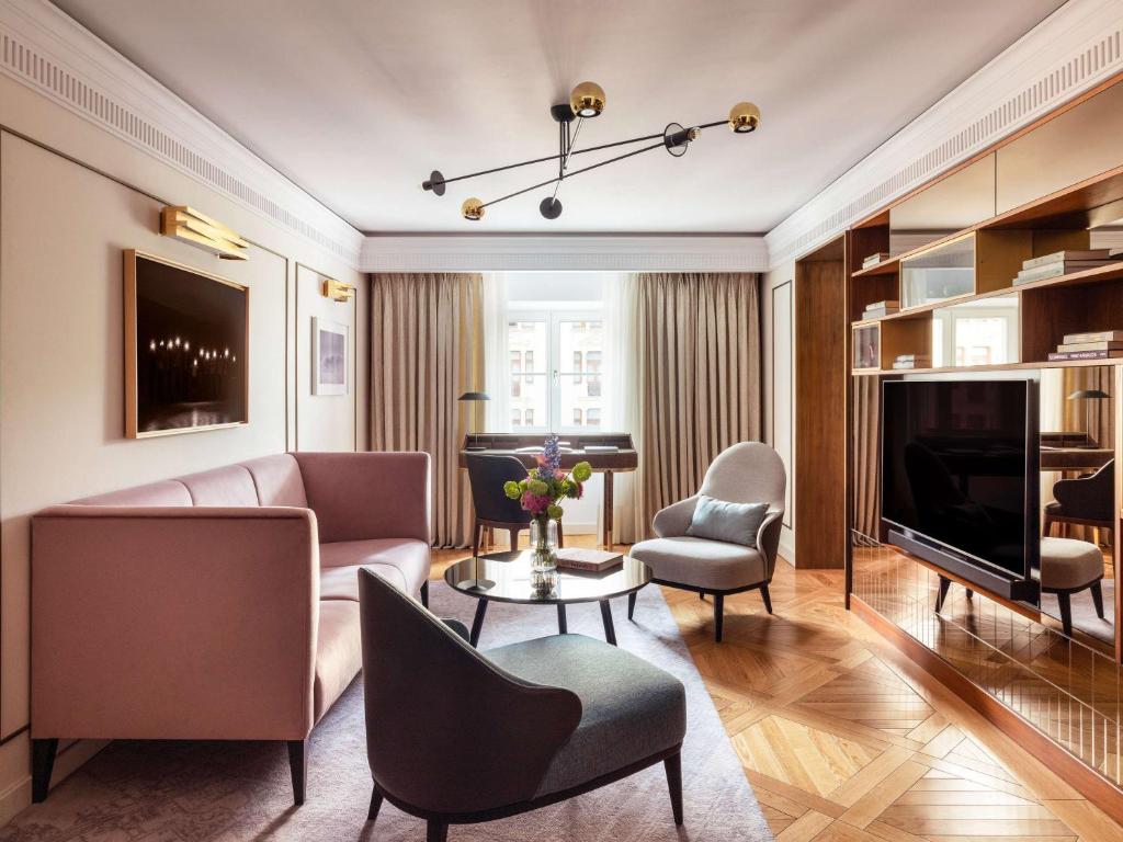 a living room with a couch and chairs and a television at Raffles Europejski Warsaw in Warsaw