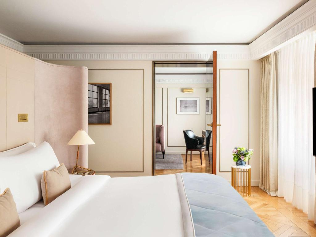 a bedroom with a white bed and a living room at Raffles Europejski Warsaw in Warsaw