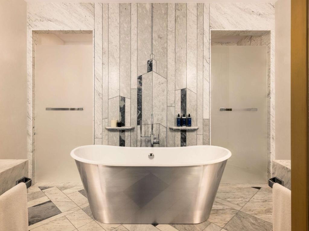 a bath tub in a bathroom with a wall at Raffles Europejski Warsaw in Warsaw