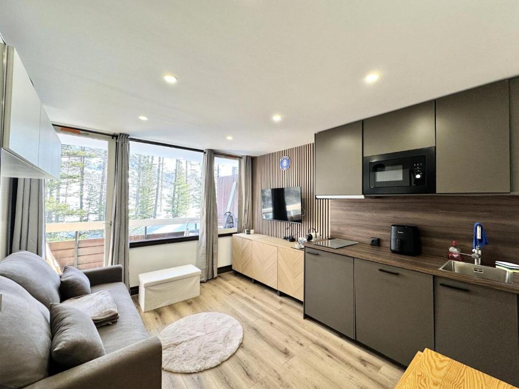 un salon avec un canapé et une cuisine dans l'établissement Résidence Le Forest - COCOON A LA MONTAGNE MAE-7911, à Vars