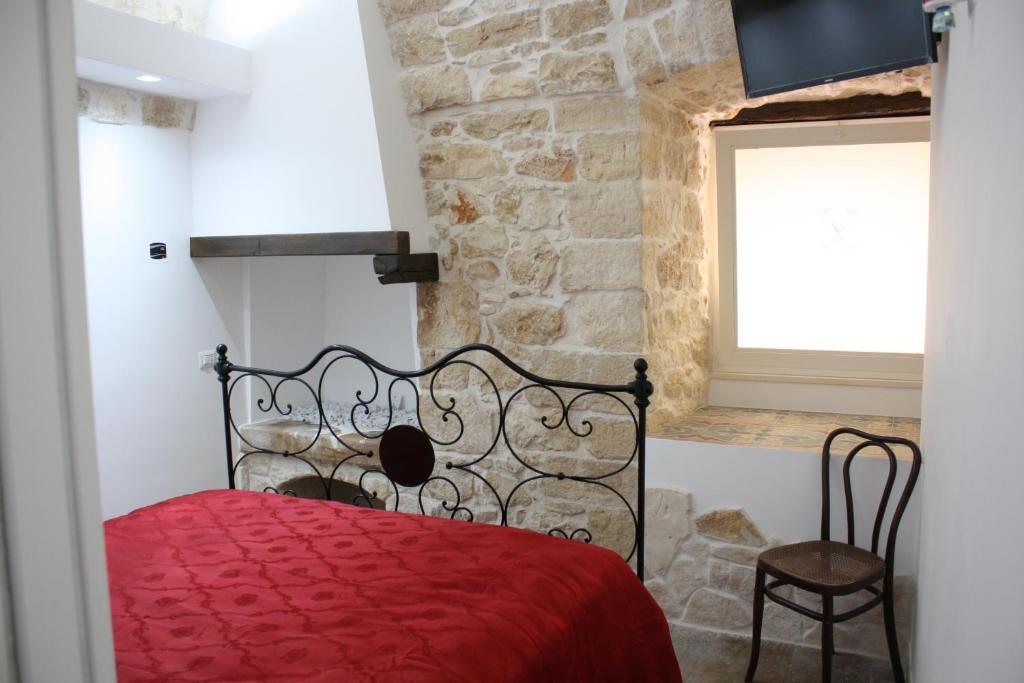 sypialnia z czerwonym łóżkiem i kamienną ścianą w obiekcie Lilla B&B w mieście Molfetta