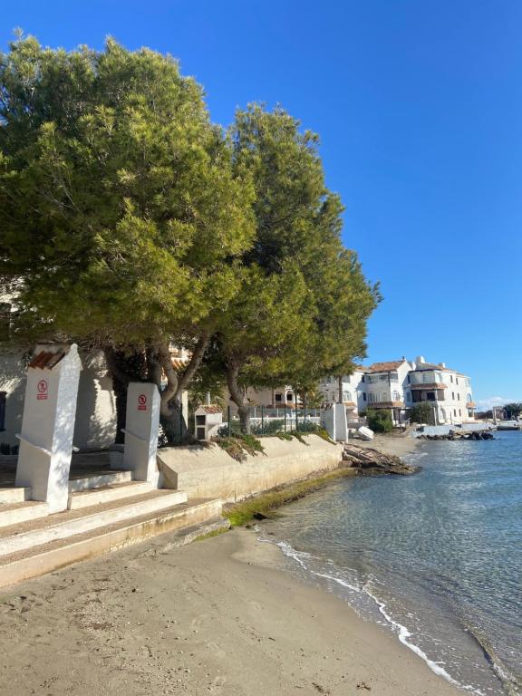 a beach with trees and houses next to the water at La Manga Caralmar Paraíso in La Manga del Mar Menor