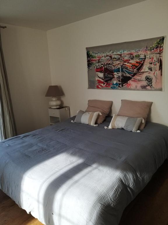 a large bed in a bedroom with a painting on the wall at Sucré salé in Le Port-des-Barques
