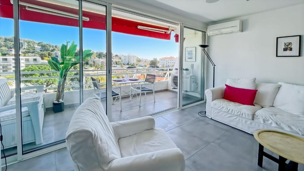 un salon avec des meubles blancs et une grande fenêtre dans l'établissement Serenity Cannes Cozy One-Bedroom, à Cannes