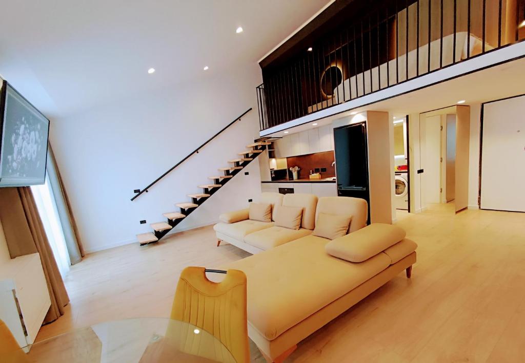 a living room with a couch and a staircase at Tirana Sunset Retreat Stylish Loft by the Lake Park in Sauk
