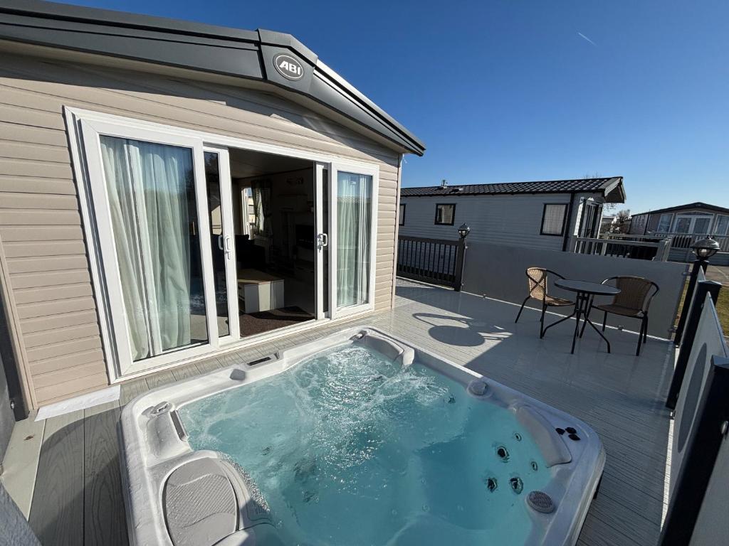 a hot tub on a deck with a patio at The Retreat 10 - Hot tub Mini Lodge, central heating, bed linen, & pet friendly - Meadow Lakes Caravan Hire in Chapel Saint Leonards
