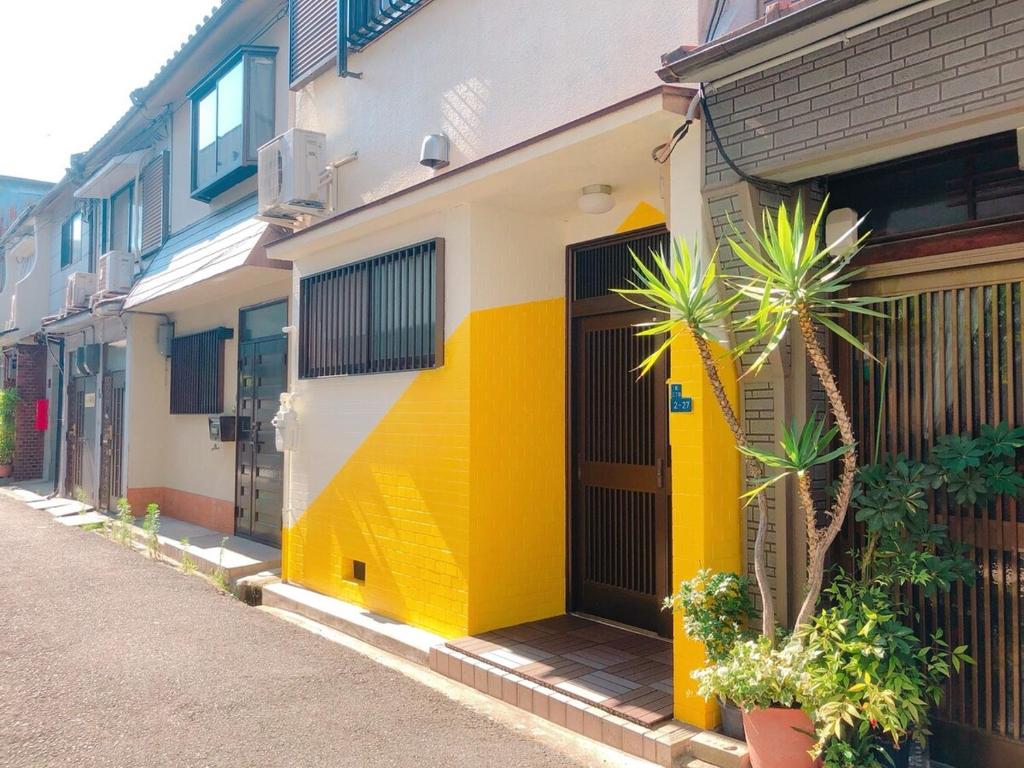 a yellow and white building with palm trees on a street at RInnオリジナル天下茶屋 松 in Osaka