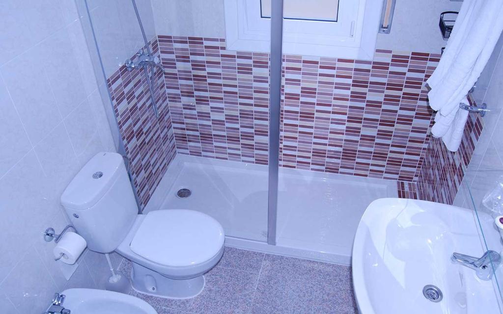 a bathroom with a toilet and a tub and a sink at Hotel Paradís in Torredembarra