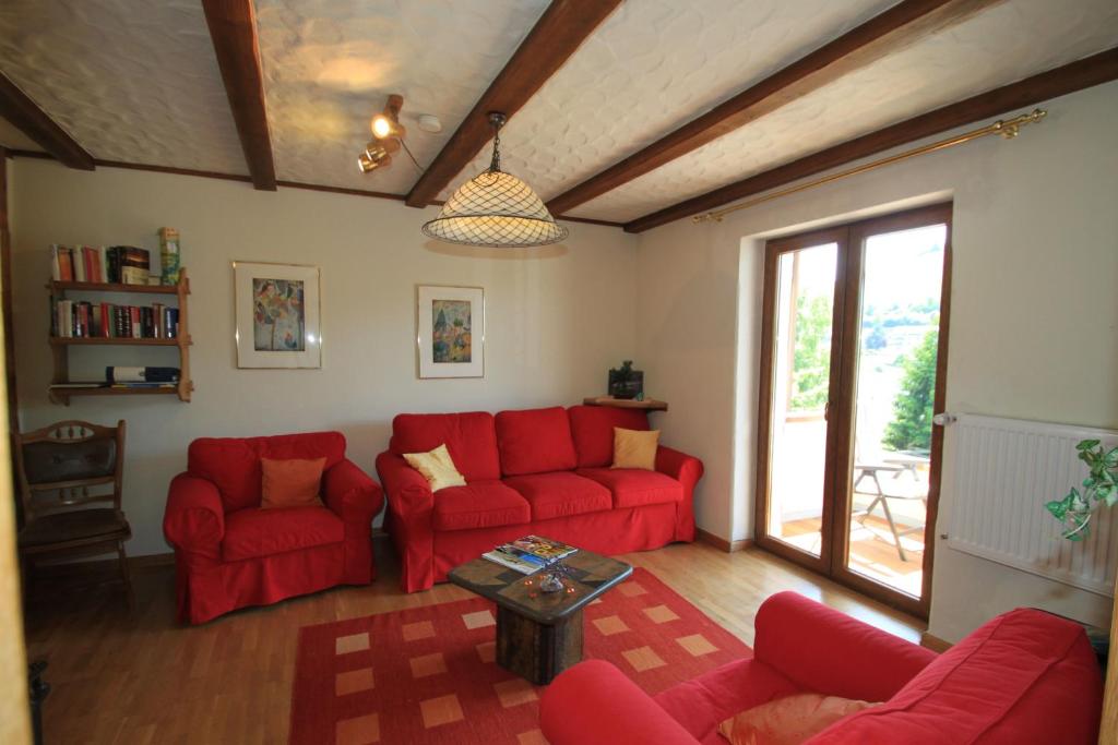 un salon avec des canapés rouges et une table dans l'établissement Simonis Privatpool, à Zell