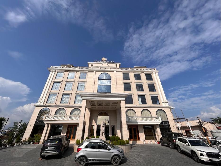 德拉敦Hotel JSR Continental的一座大楼，前面停满了汽车