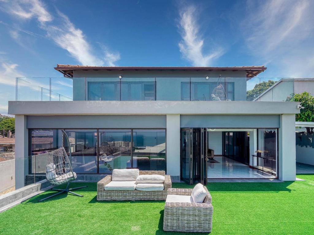 a house with a green yard with two chairs at At 40 Oceanview in Durban