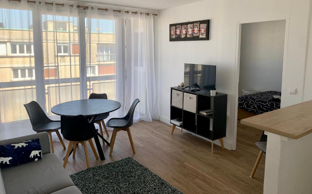 un salon avec une table, des chaises et une télévision dans l'établissement Les Clés de Saint-Jean - Prox Port et Centre Ville, à Caen