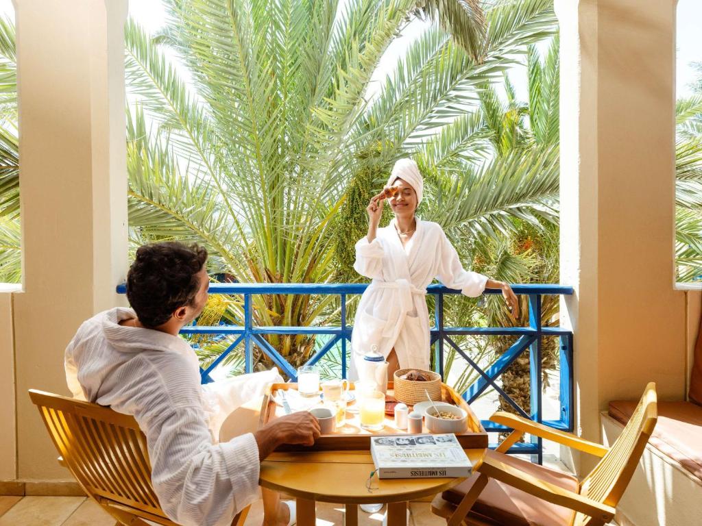 a man and woman sitting at a table talking on a cell phone at Le Médina Essaouira Thalassa Sea & Spa - MGallery Collection in Essaouira