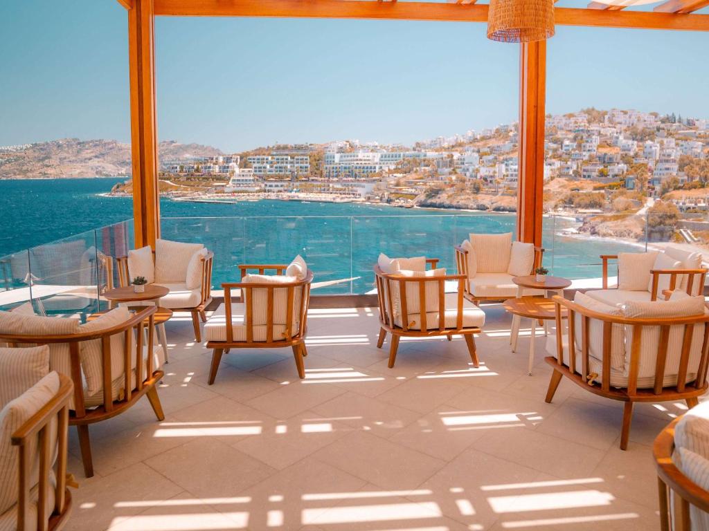a room with chairs and tables and a large window at The Bodrum Hotel Yalikavak - MGallery Collection in Yalıkavak