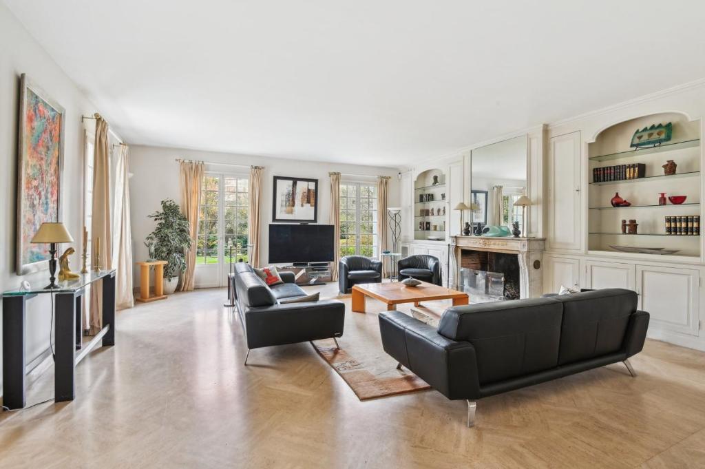 Il comprend un salon doté d'un mobilier noir et d'une télévision. dans l'établissement La Maison des Rois, à Rueil-Malmaison