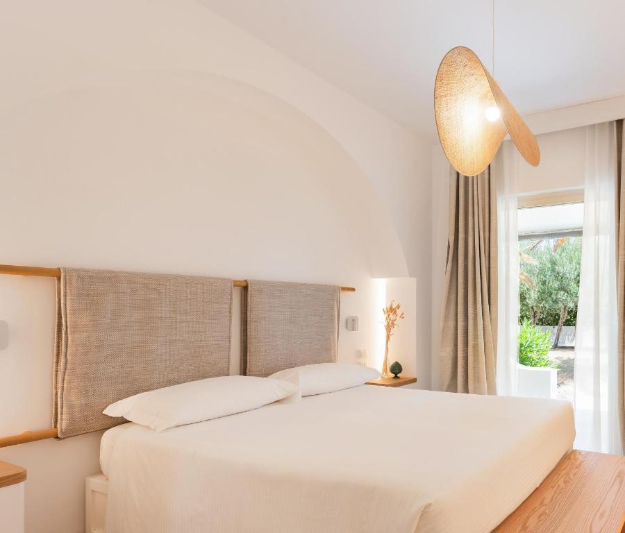 a bedroom with a large white bed and a window at Ostuni a Mare in Ostuni