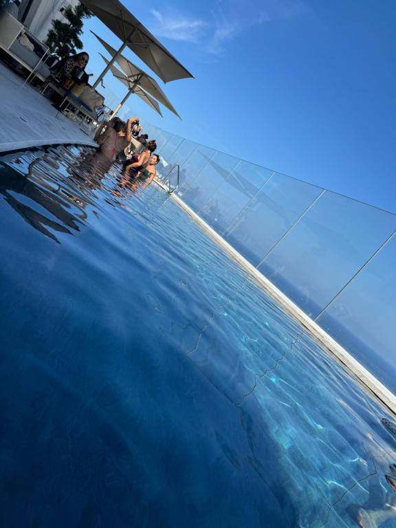 a group of people in the water in a swimming pool at Sea view Mercury Tower, Rooftop infinity Pool in St. Julianʼs
