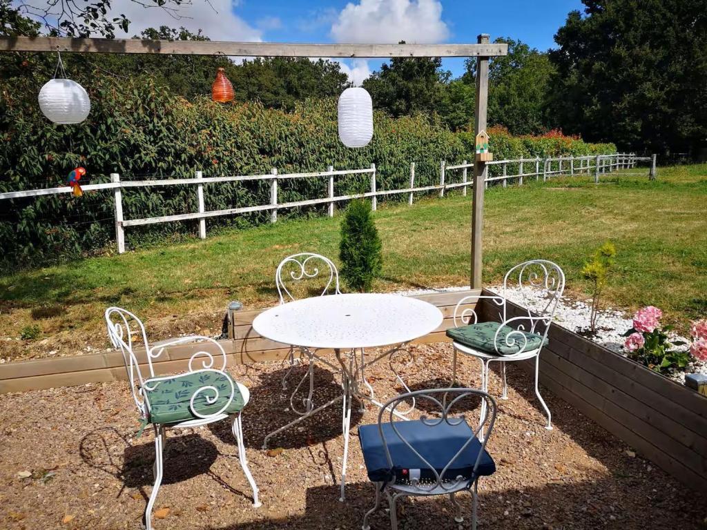 une table et des chaises assises dans une cour avec une clôture dans l'établissement Maison berrichonne au calme avec jardin et cheminée près de Châteauroux - FR-1-591-717, à Meunet-Planches