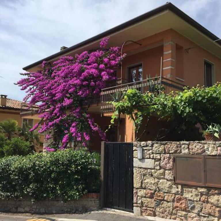 a house with purple flowers on the side of it at Residenza Bouganville in Torri del Benaco