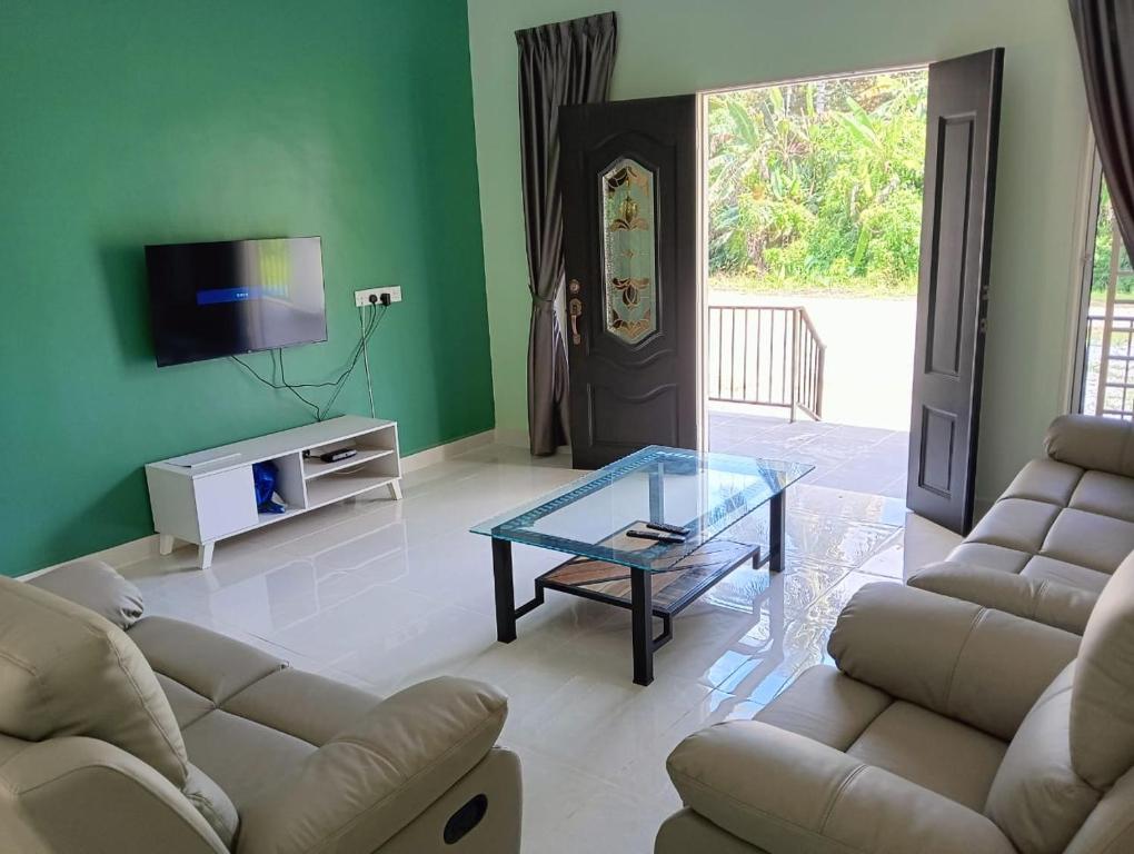 a living room with two couches and a glass table at Nok D'Jelutong Homestay Sik Kedah in Sik