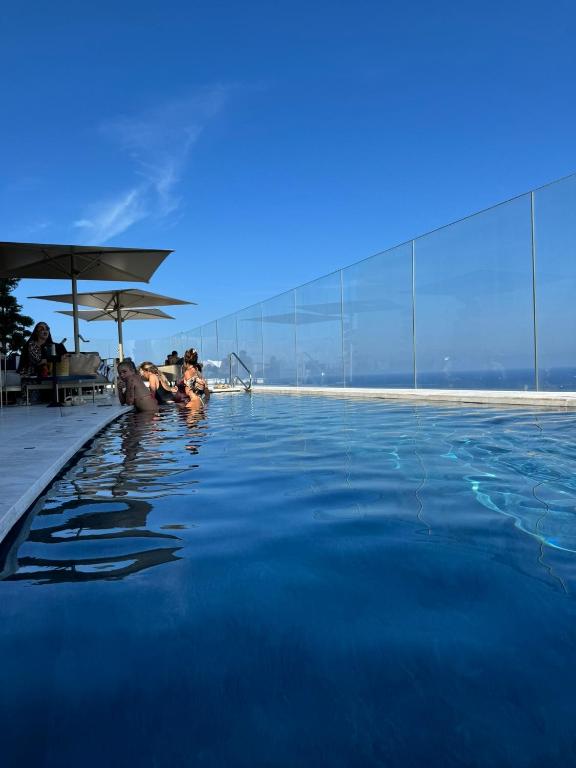 a group of people swimming in a swimming pool at Sea view Mercury Tower, Rooftop infinity Pool in St. Julianʼs
