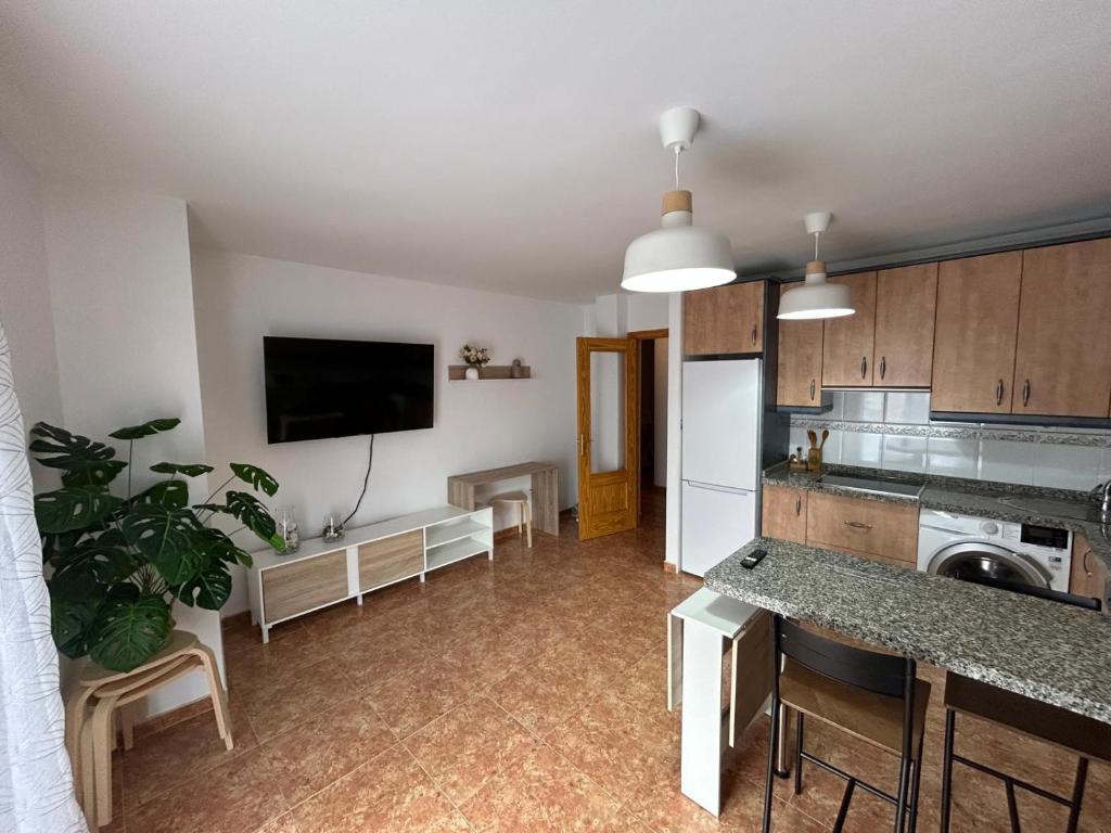 Una cocina con sala de estar con refrigerador y televisor. en Apartamento, en Carboneras