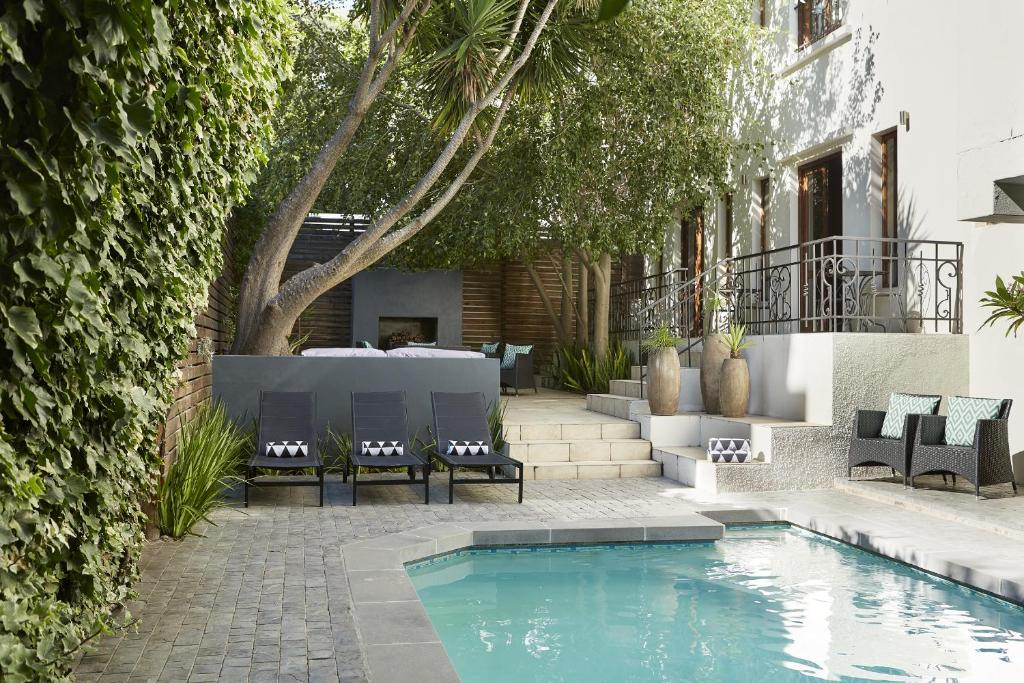 a swimming pool in a yard with chairs next to a building at Bayflowers Guest House in Cape Town