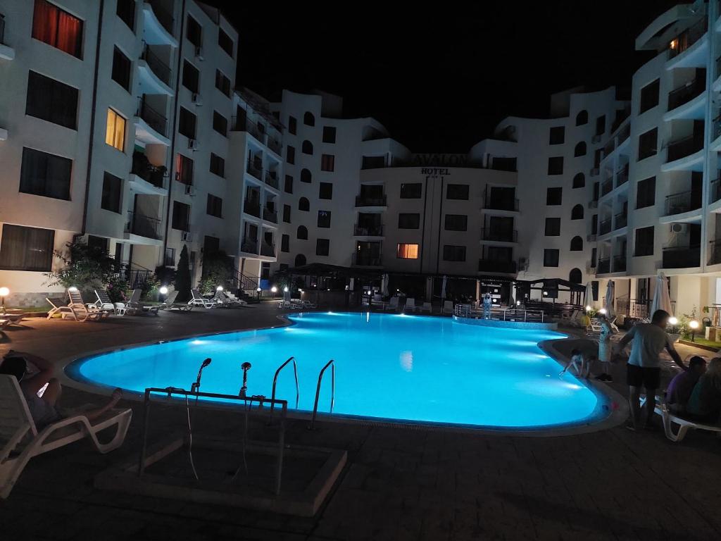 a large blue swimming pool at night with buildings at Avalon Lux in Sunny Beach