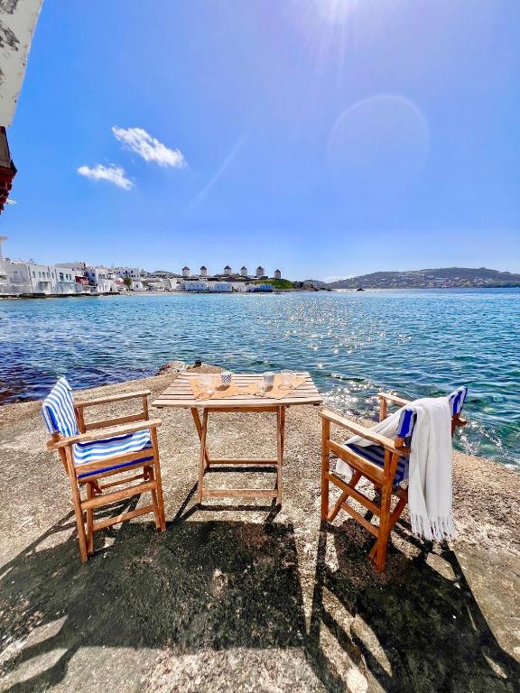a table and two chairs sitting next to the water at Kyma Apartments-Little Venice,Mykonos in Mikonos