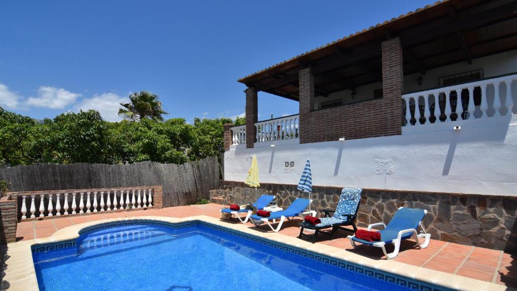 basen z krzesłami i dom w obiekcie Villa La Lomilla w mieście Nerja