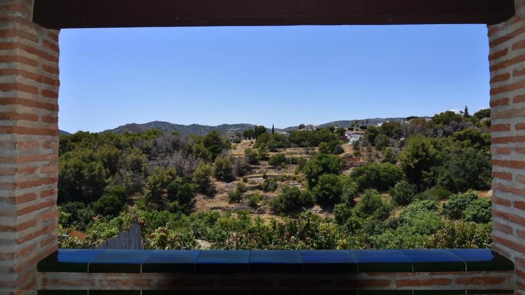 okna z widokiem na wzgórze z drzewami w obiekcie Villa La Lomilla w mieście Nerja