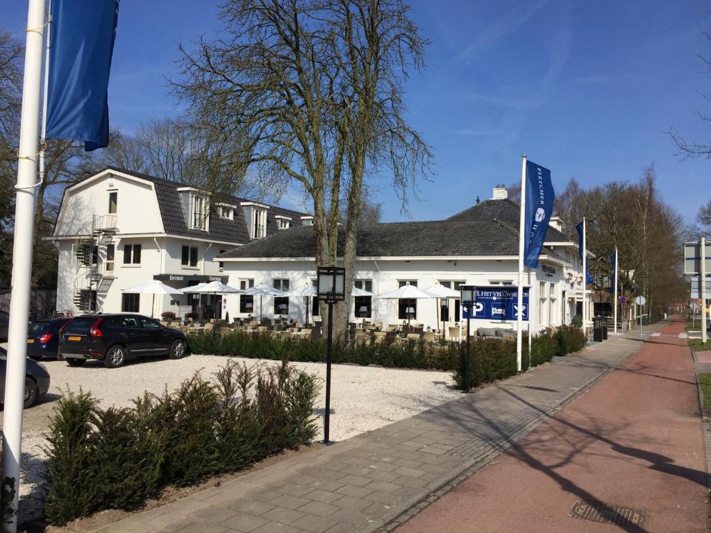 ein weißes Gebäude mit einem davor geparkt in der Unterkunft Fletcher Hotel Het Veluwse Bos in Beekbergen