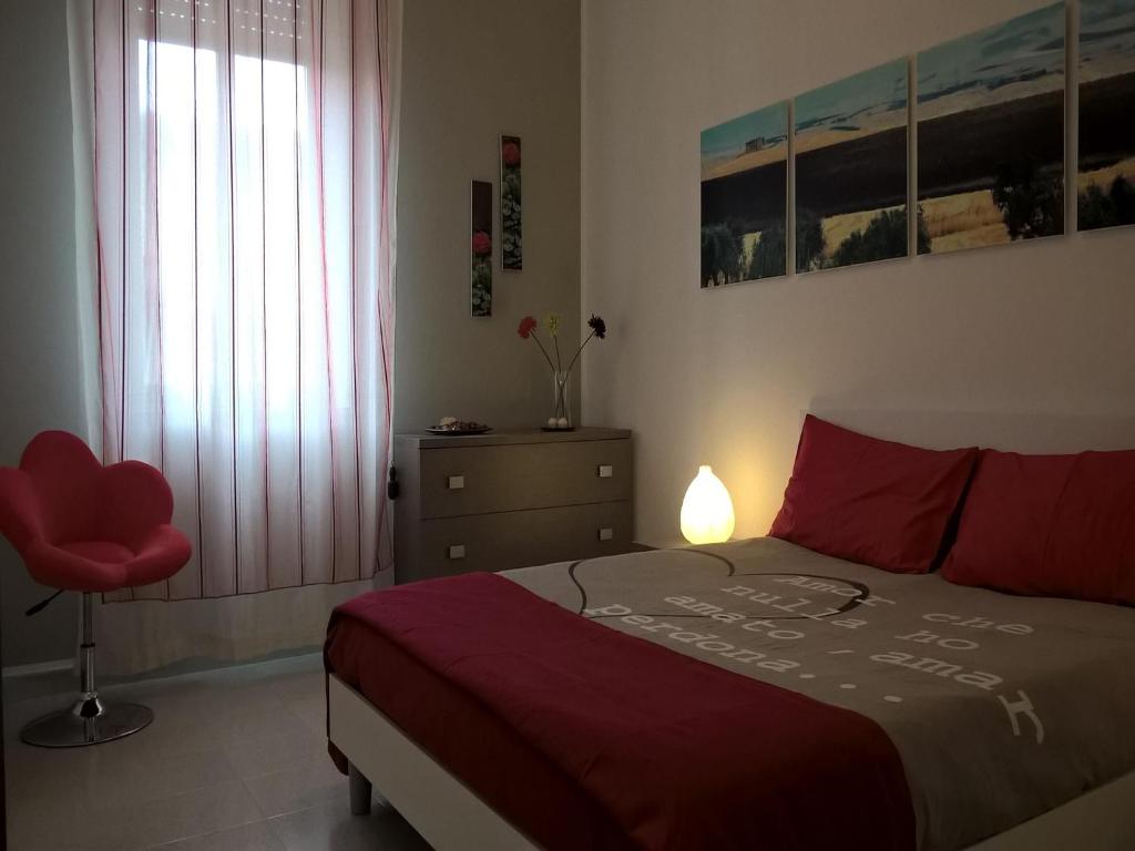 a bedroom with a red bed and a red chair at Casa Vacanze A Pennichella in Canicattini Bagni