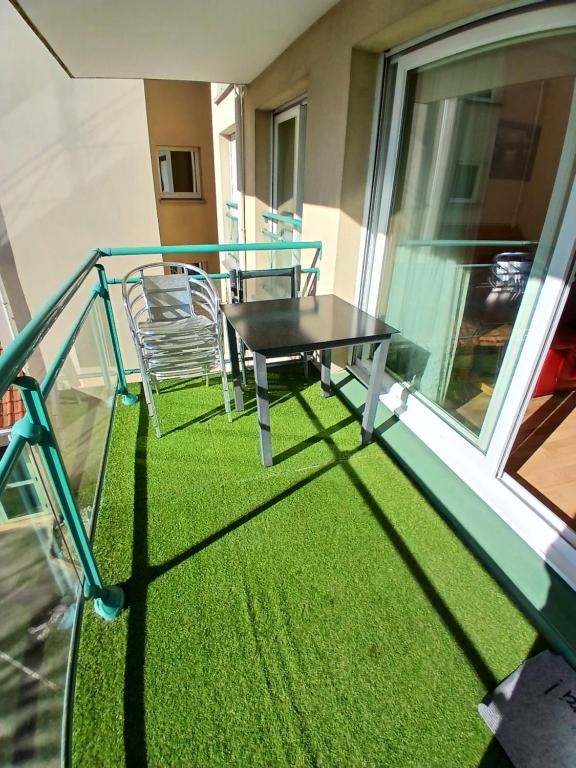 einen Tisch und Stühle auf einem Balkon mit Gras in der Unterkunft Appar bray-dunes in Bray-Dunes