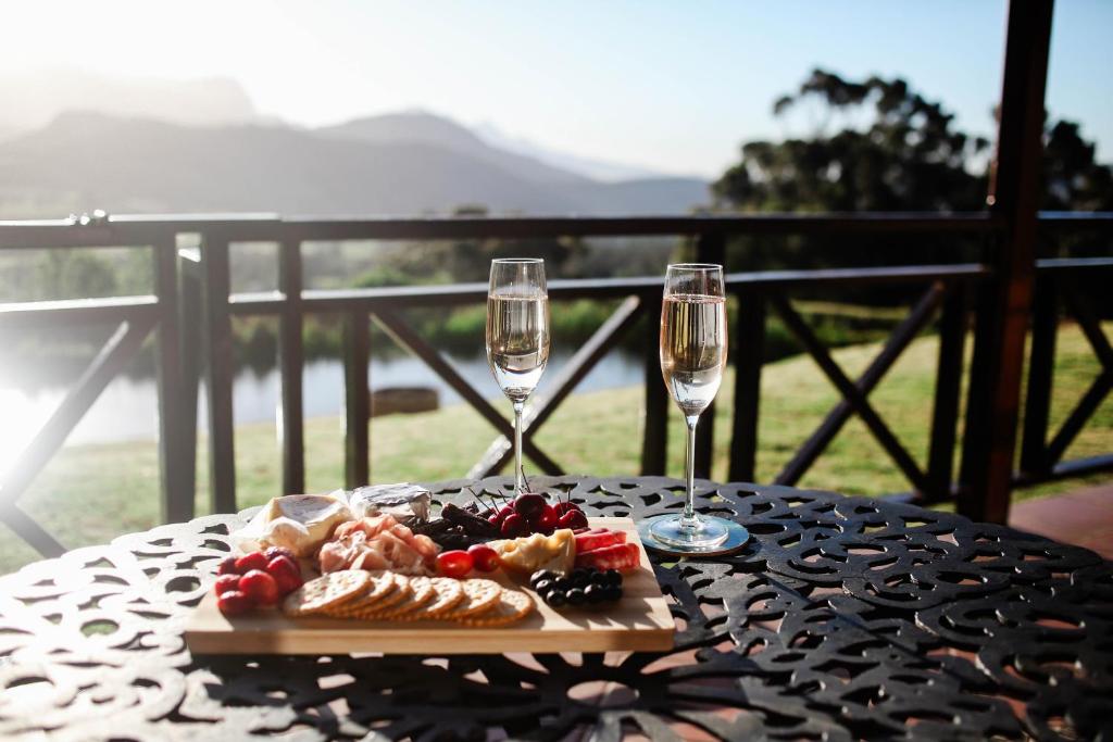 a table with a plate of food and two wine glasses at MontMartre Chalets & Venue in Franschhoek