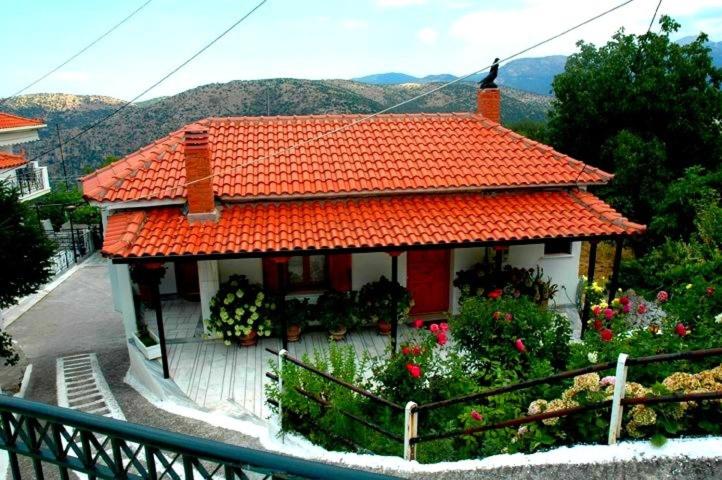a small house with an orange roof with flowers at Dafni Apartments in Kastri